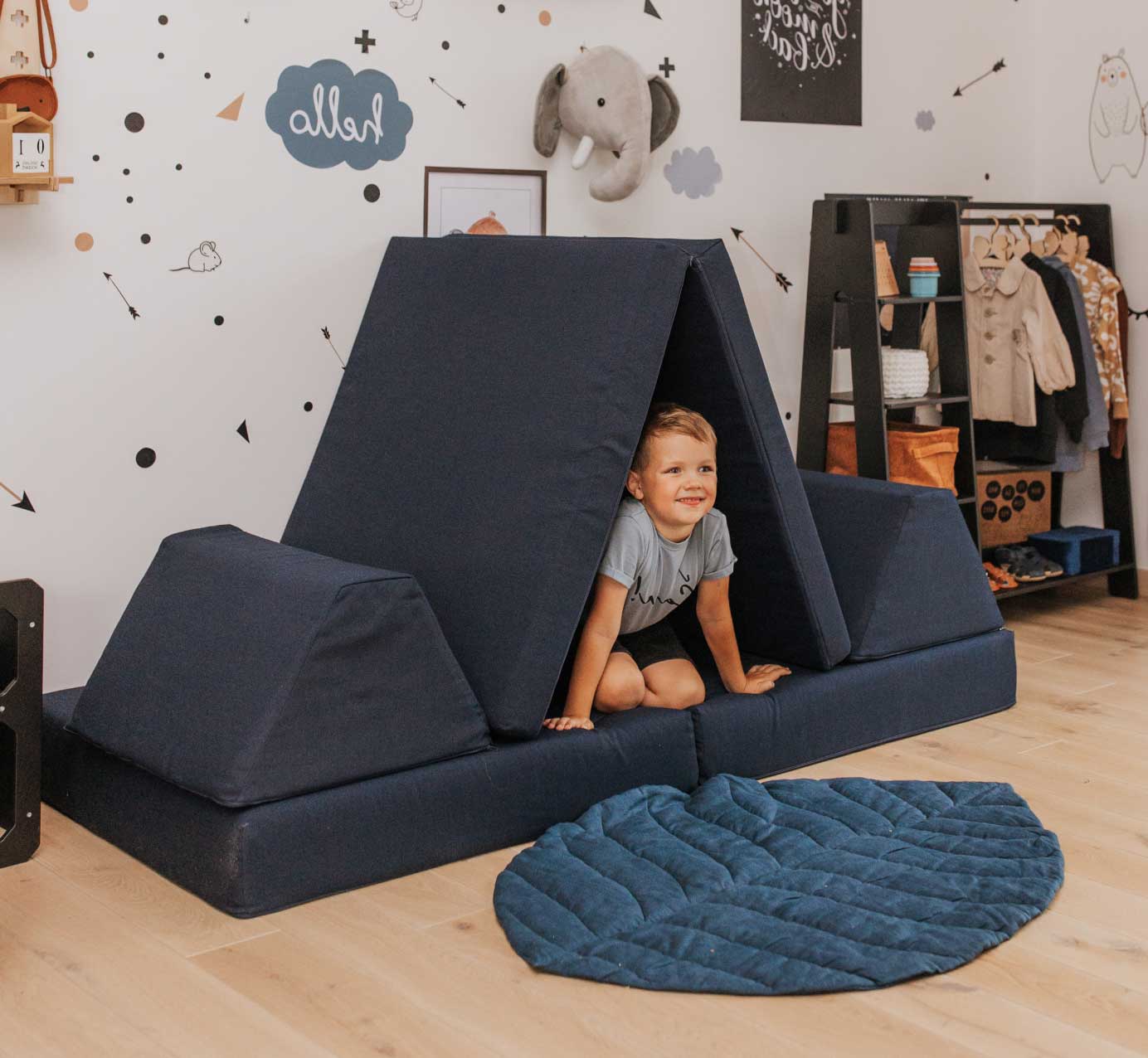 A toddler boy inside a navy blue Monboxy activity play set fort