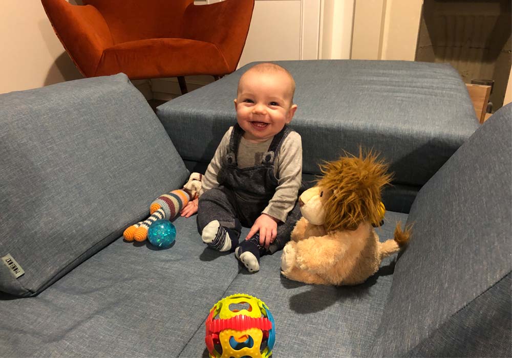 A baby boy sitting on a navy blue play sofa set