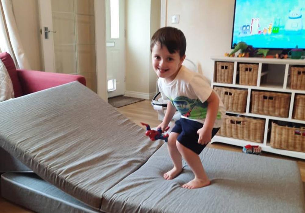 A happy boy jumping on his grey Monboxy play sofa set