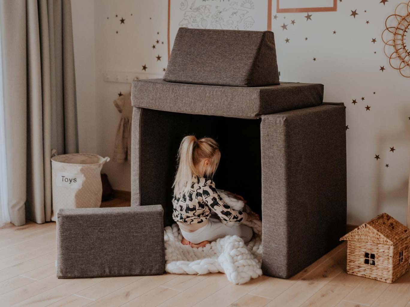 A toddler girl playing inside her dark brown Monboxy set