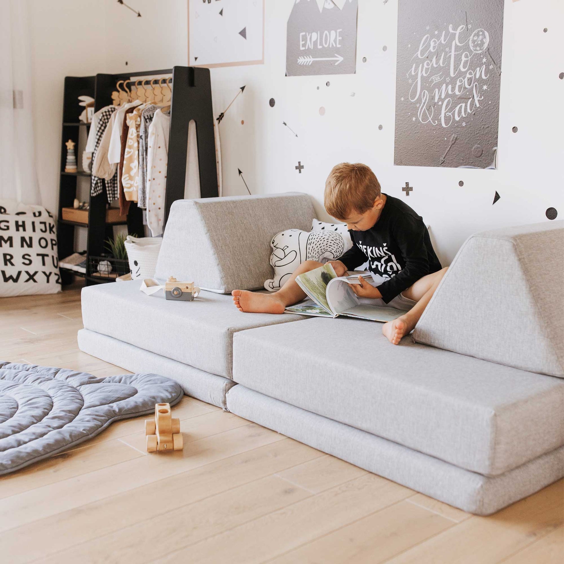 A boy reading a book while sitting on his grey Monboxy foam play gym