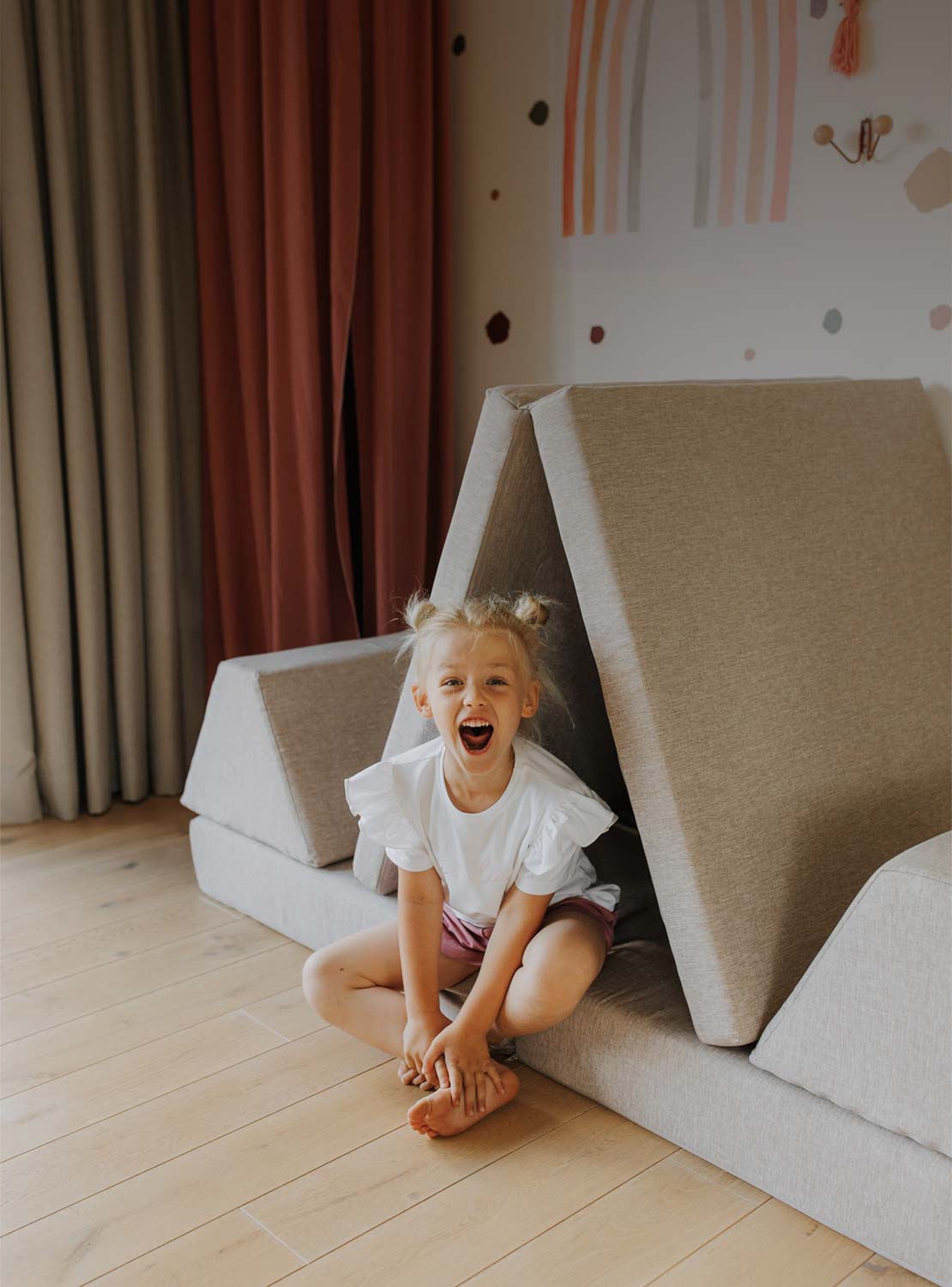 A happy girl with a big smile sitting on her Monboxy play sofa