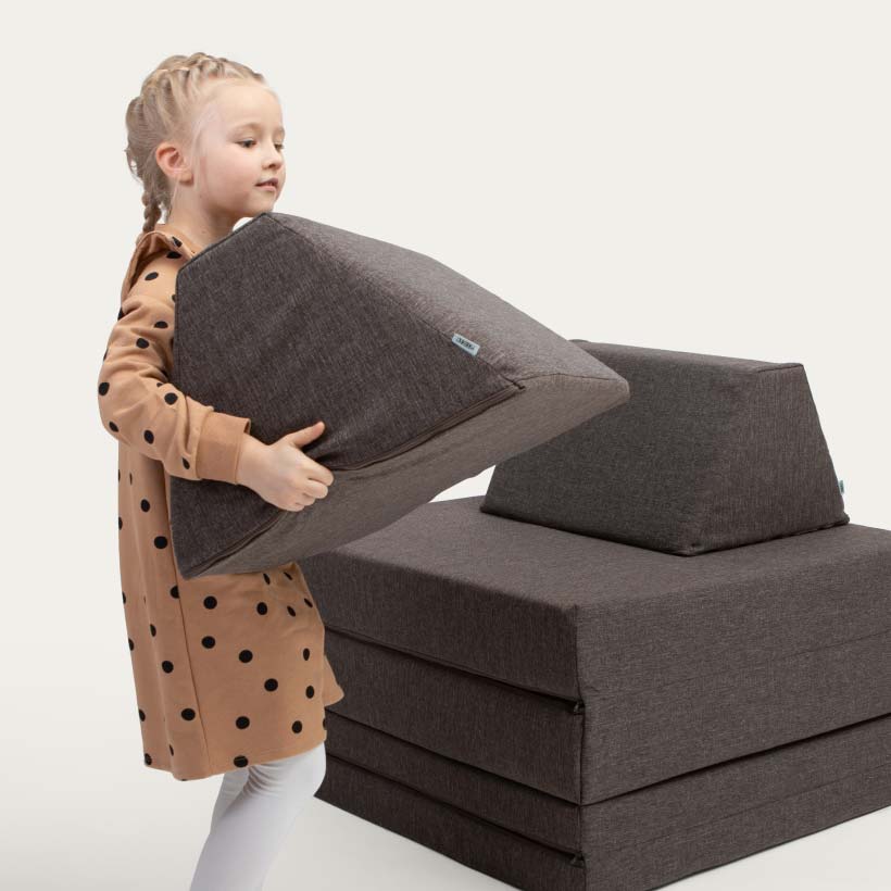 A girl carrying a brown Monboxy activity set trapezoidal block