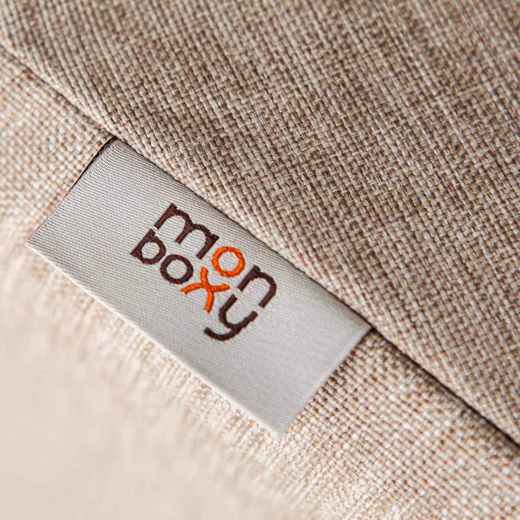 Close-up of a beige fabric label with the brand name "Monboxy" embroidered in brown and orange on it, ideal as a Montessori gift.