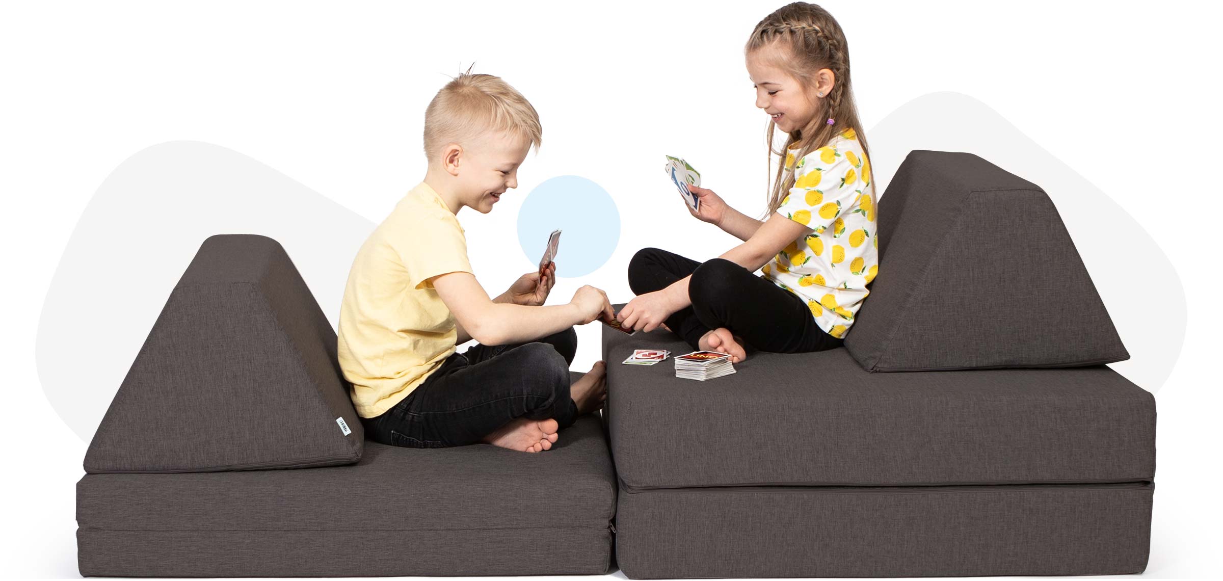 Kids sitting and playing cards on a dark brown Monboxy foam block set for kids