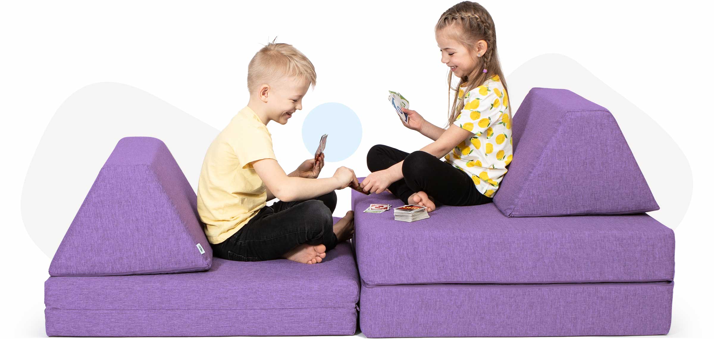 Kids sitting and playing cards on a purple Monboxy activity couch