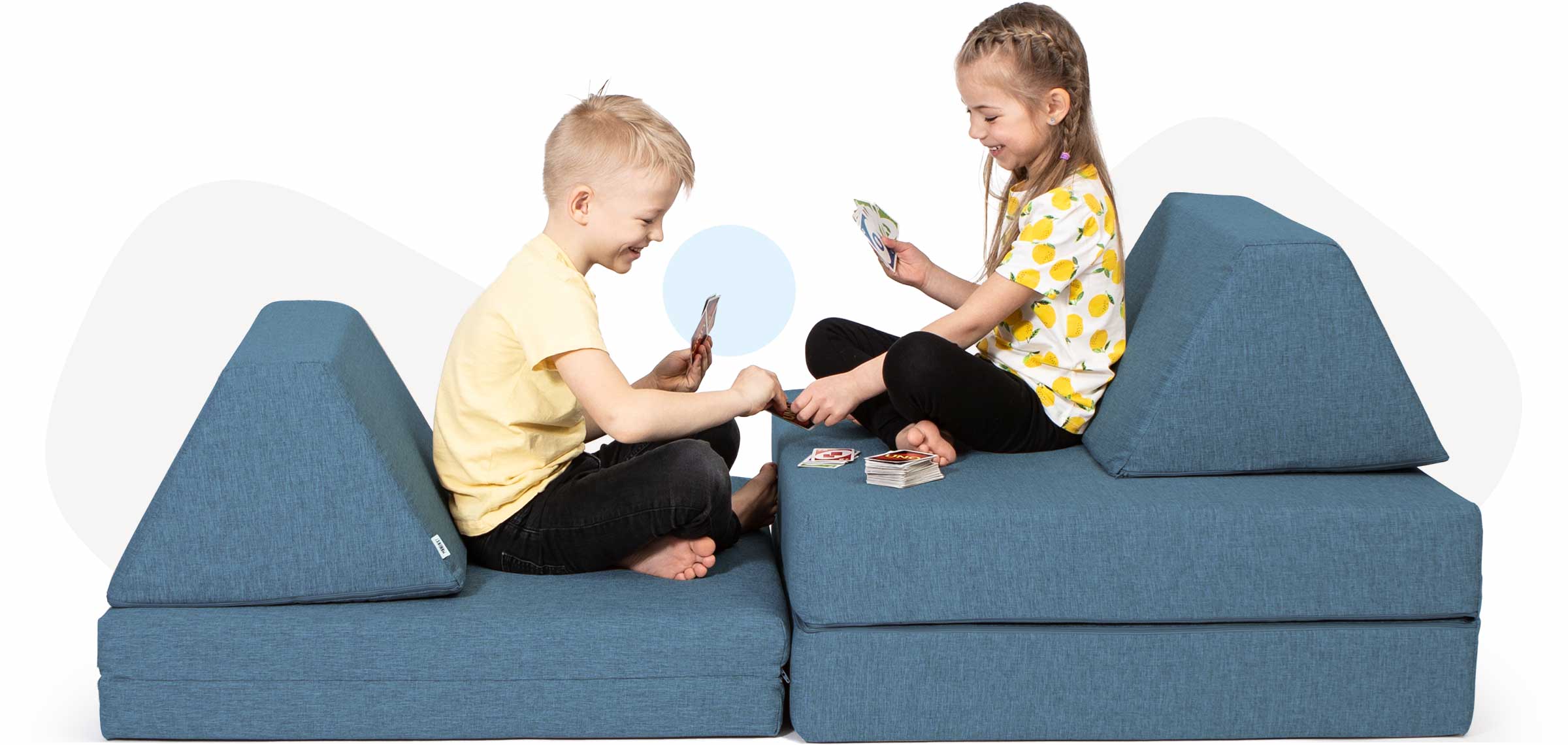 Kids sitting and playing cards on a turquoise Monboxy soft blocks set