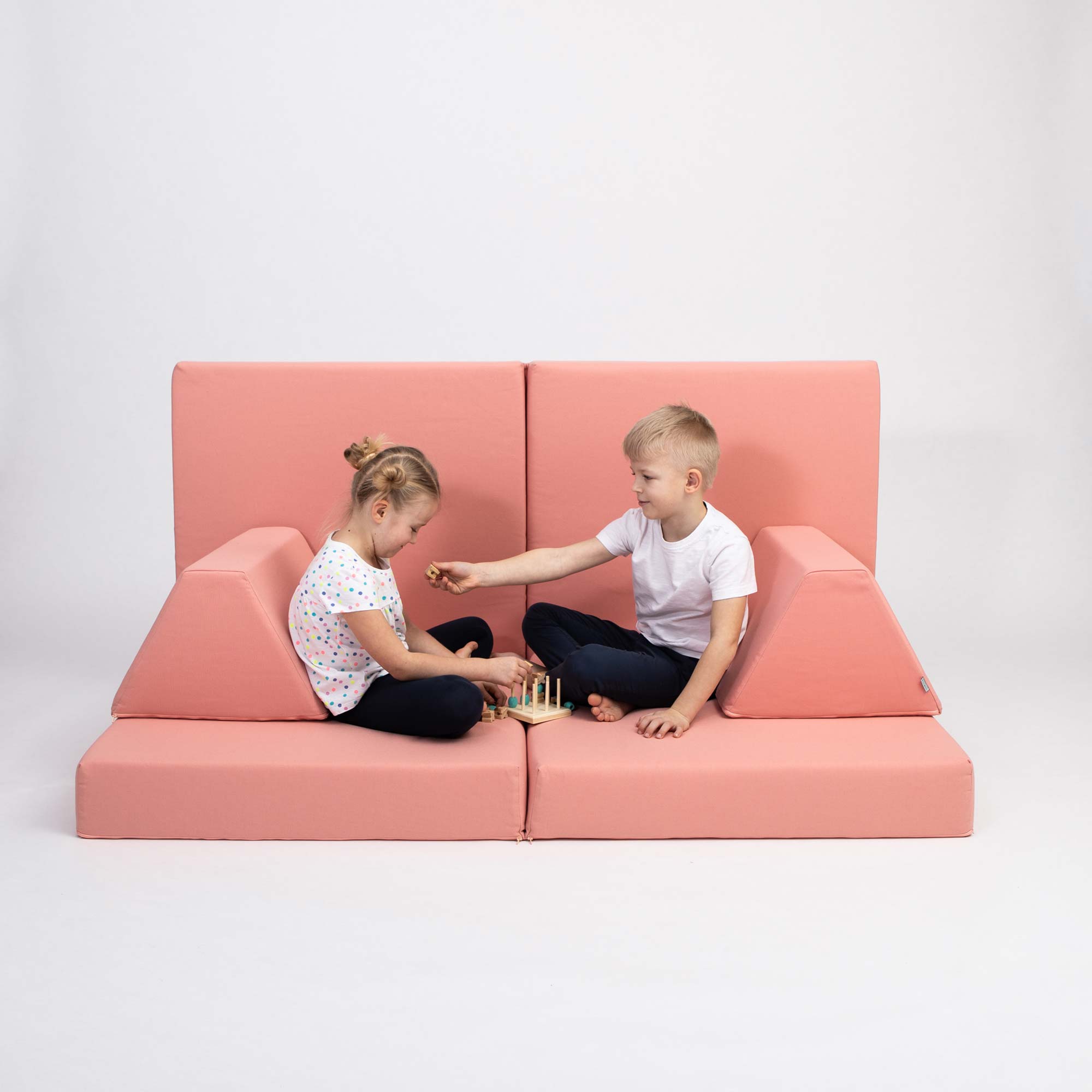 Brother and sister playing while sitting on their salmon pink Monboxy foam sofa set for kids
