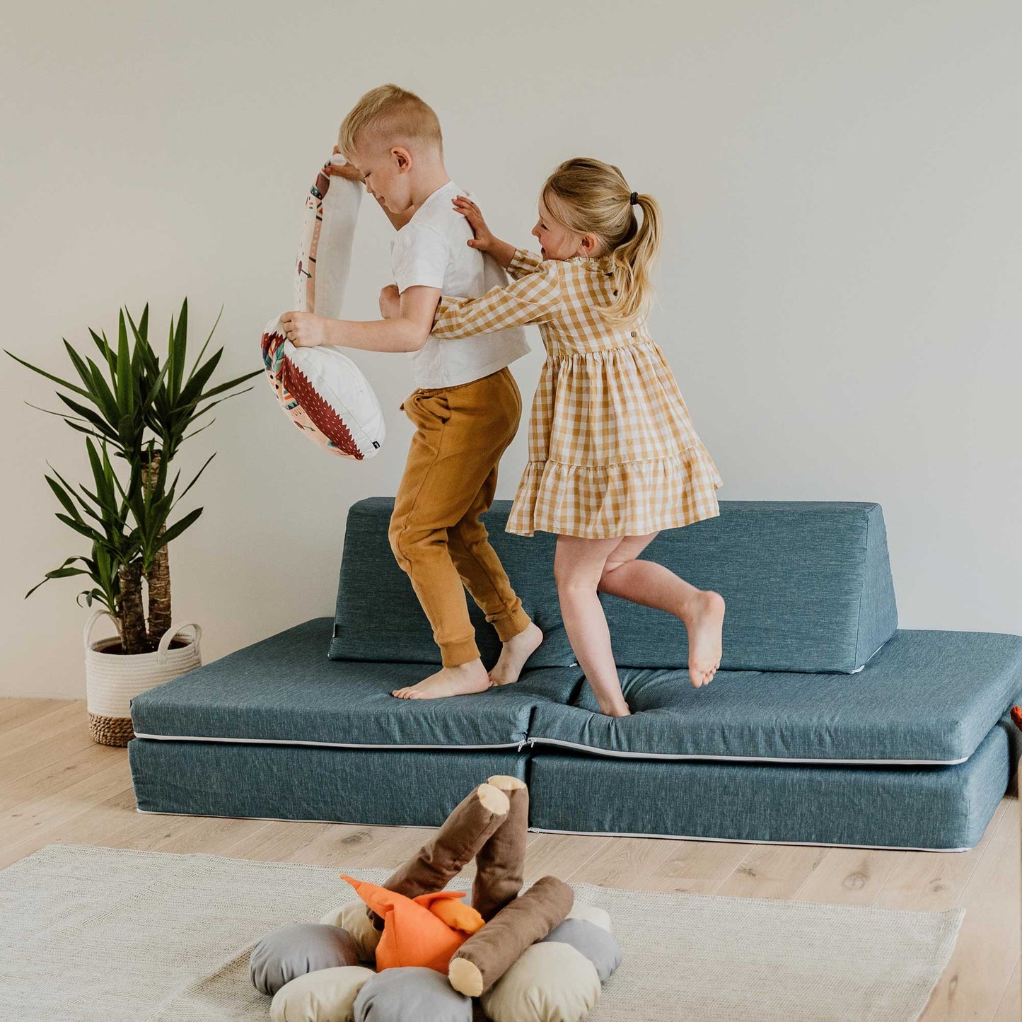 Brother and sister actively playing on their turquoise Monboxy foam play couch set