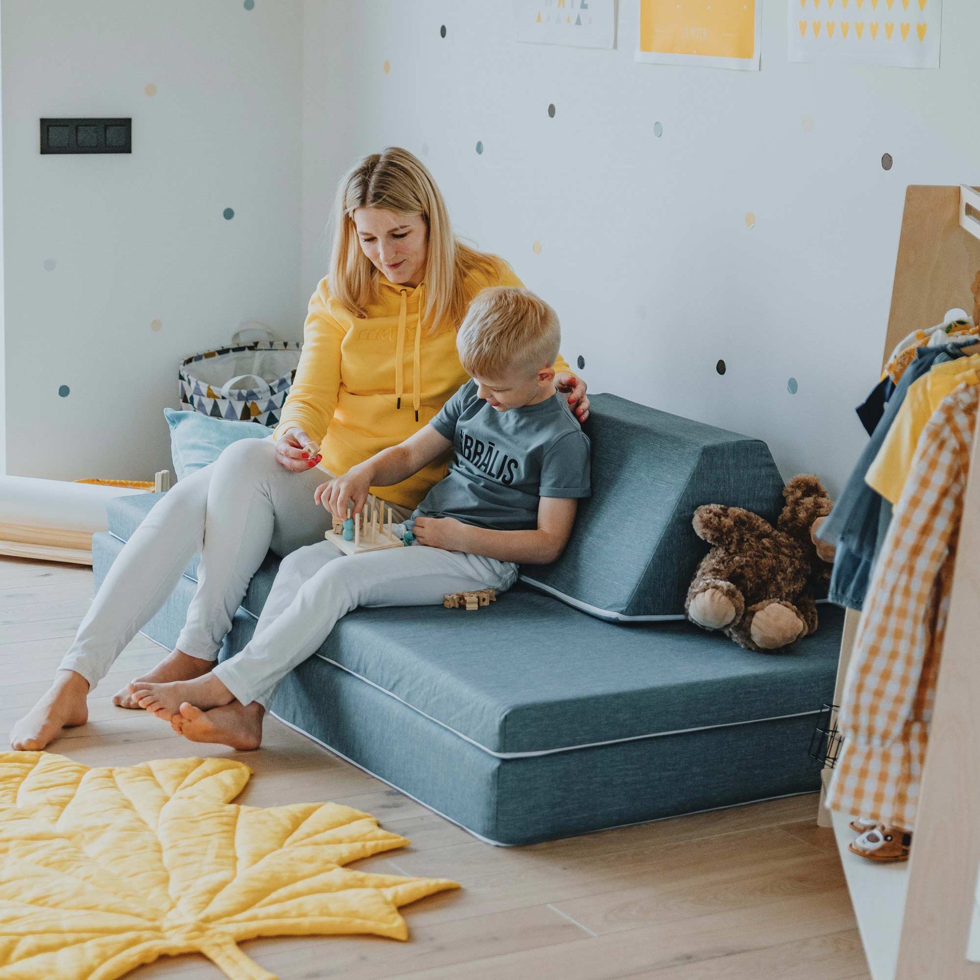 Mother and son playing with wooden toys while sitting on a turquoise Monboxy activity couch