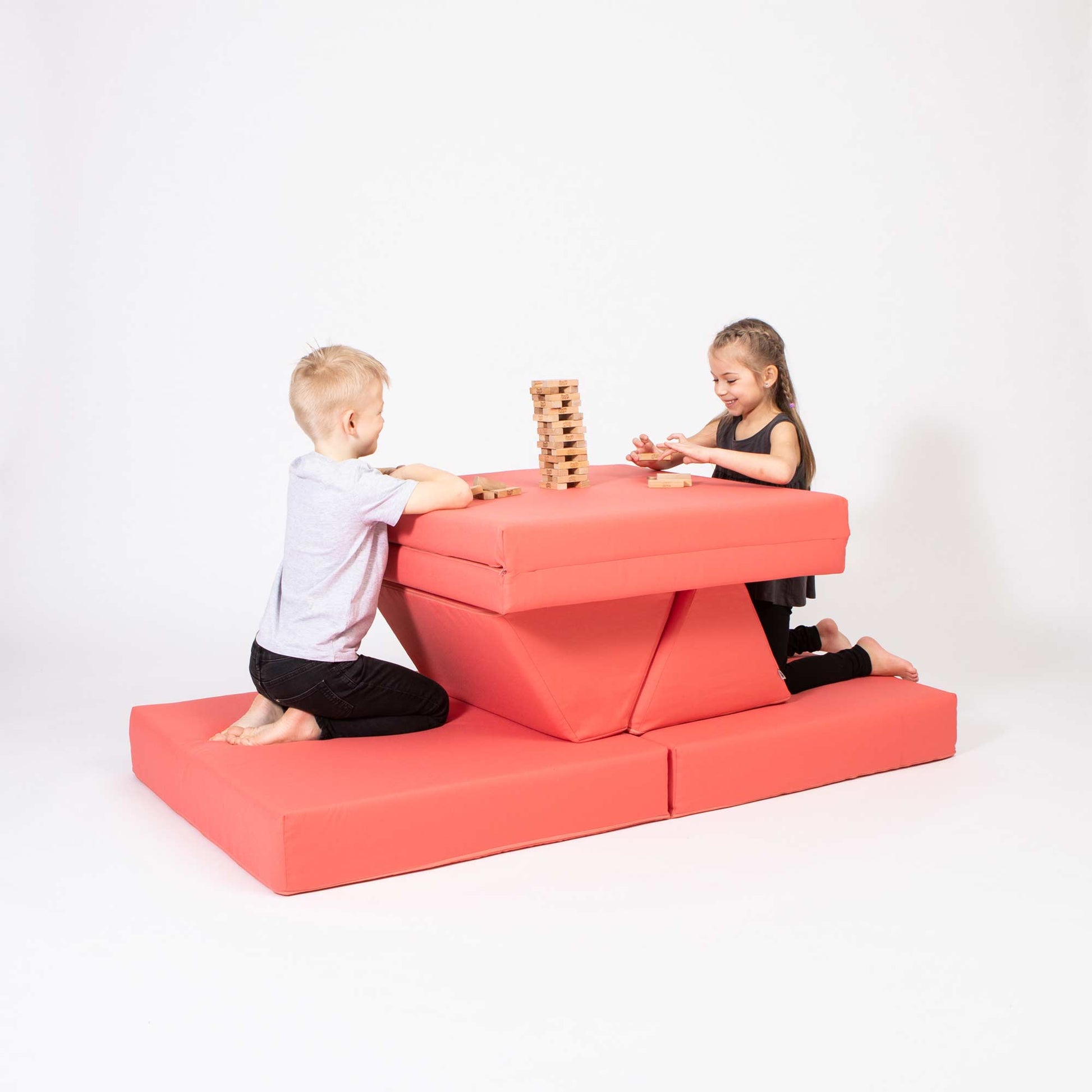 A boy and a girl playing jenga on their coral Monboxy foam playset
