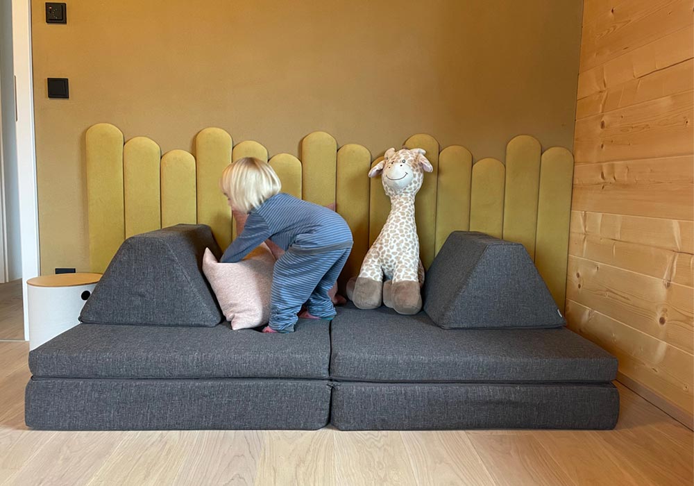 A toddler actively playing with his Monboxy activity couch set