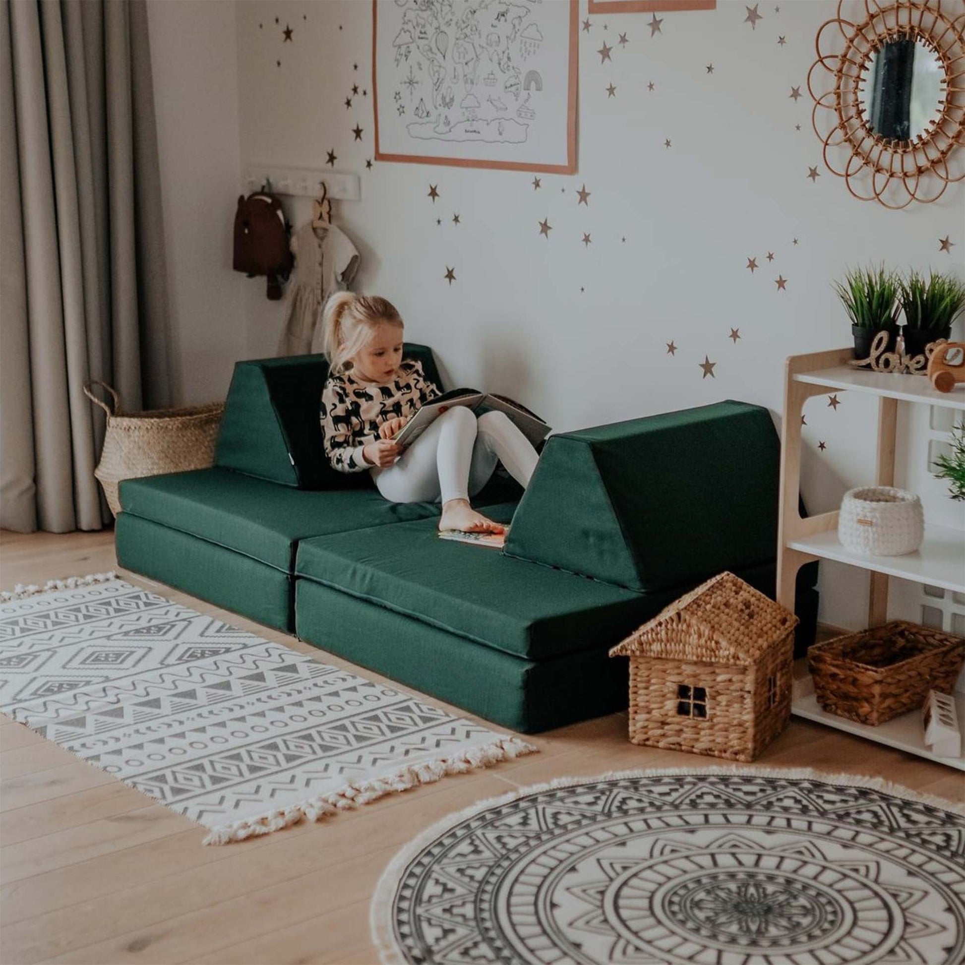 A girl reading a book while relaxing on her deep green Monboxy play sofa
