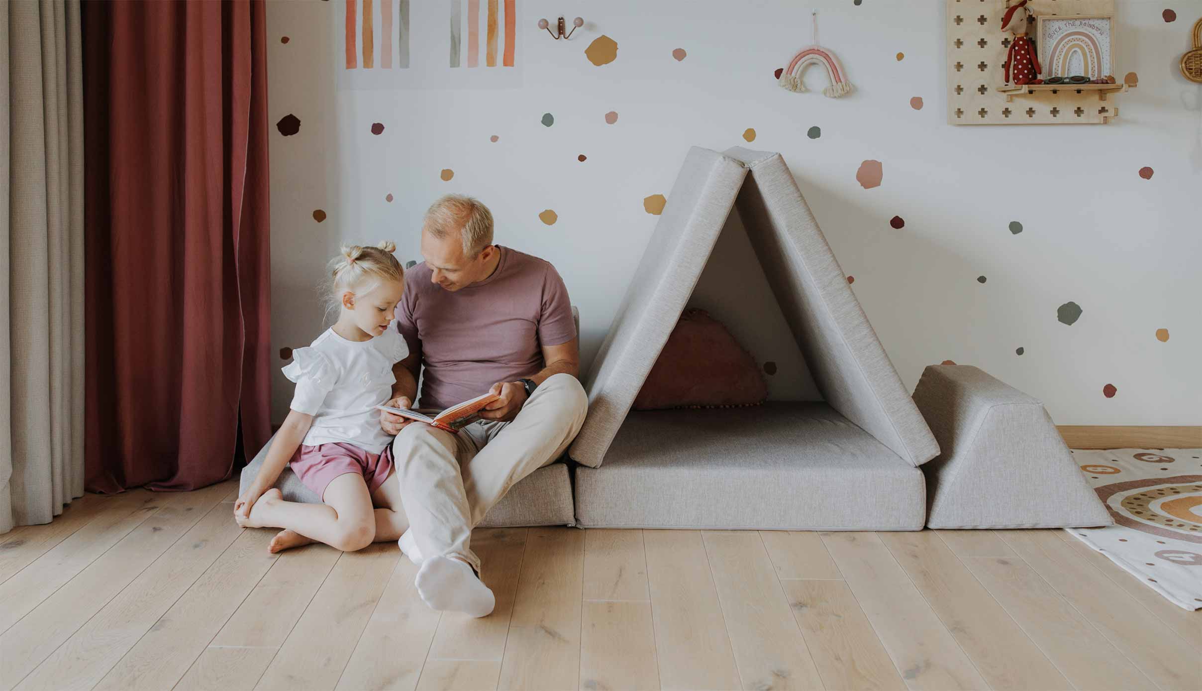 Father and daughter reading a book seated on their Monboxy play sofa