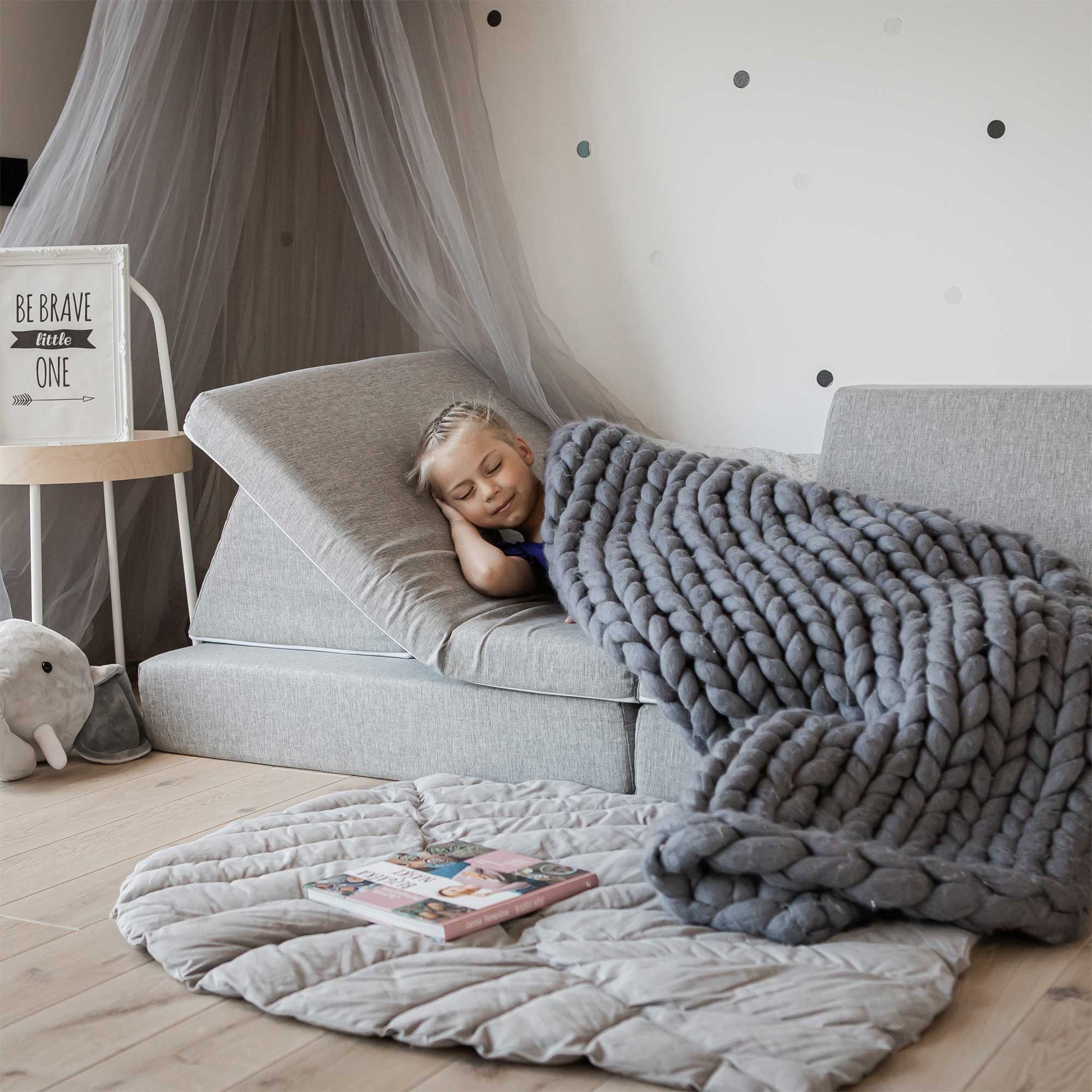 A girl sleeping on her grey Monboxy sofa, covered with a blanked