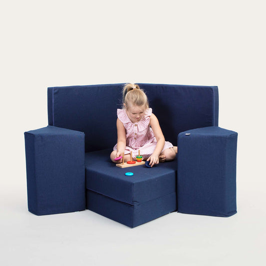 A toddler girl playing with her toys on a Navy blue Monboxy activity couch.