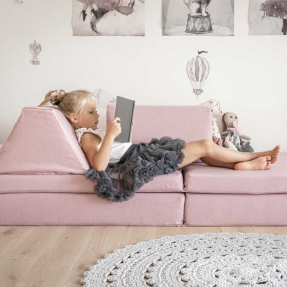 A girl reading a book while laying down on a pink Monboxy foam climb blocks set