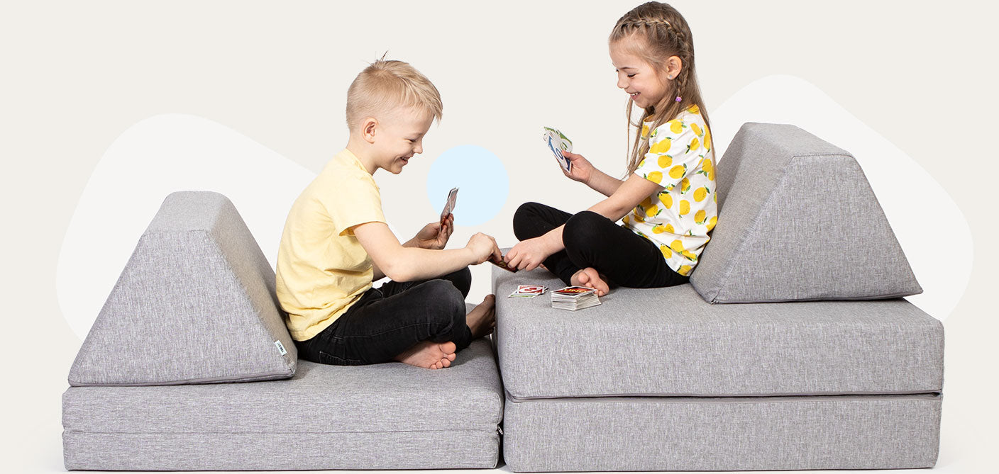 Two toddlers playing cards on a grey Monboxy activity sofa set