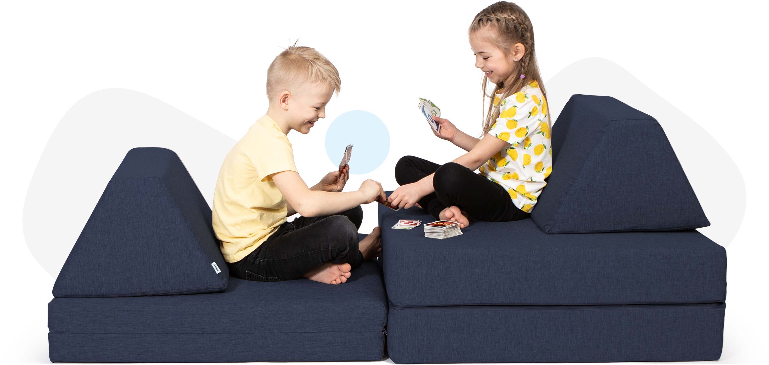 Kids sitting and playing cards on a navy blue Monboxy sofa