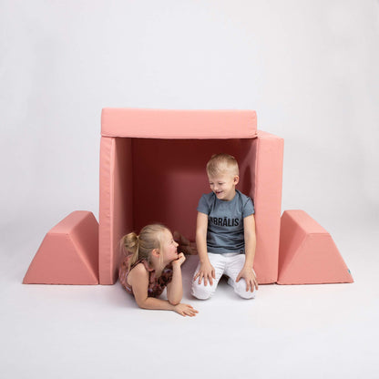 Siblings playing inside a salmon pink Monboxy play sofa