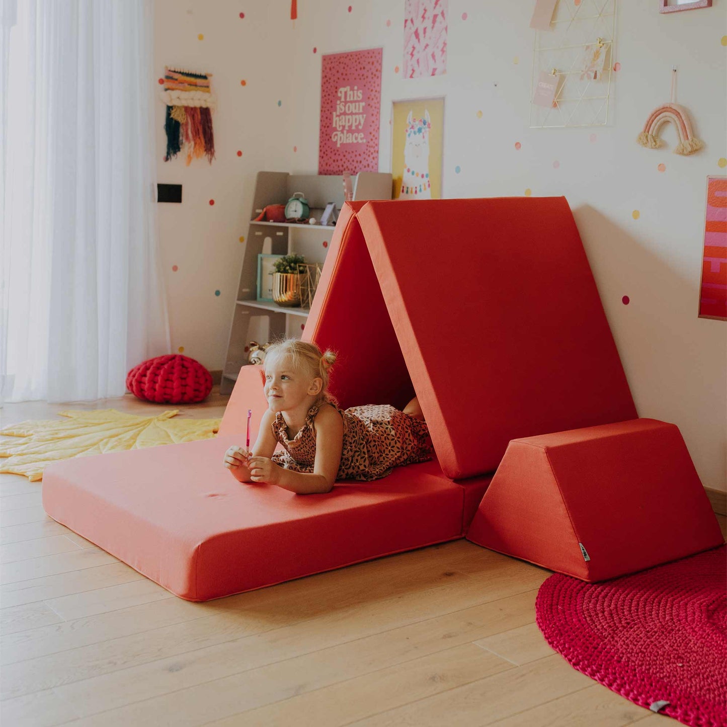 A girl laying in her coral play sofa fort