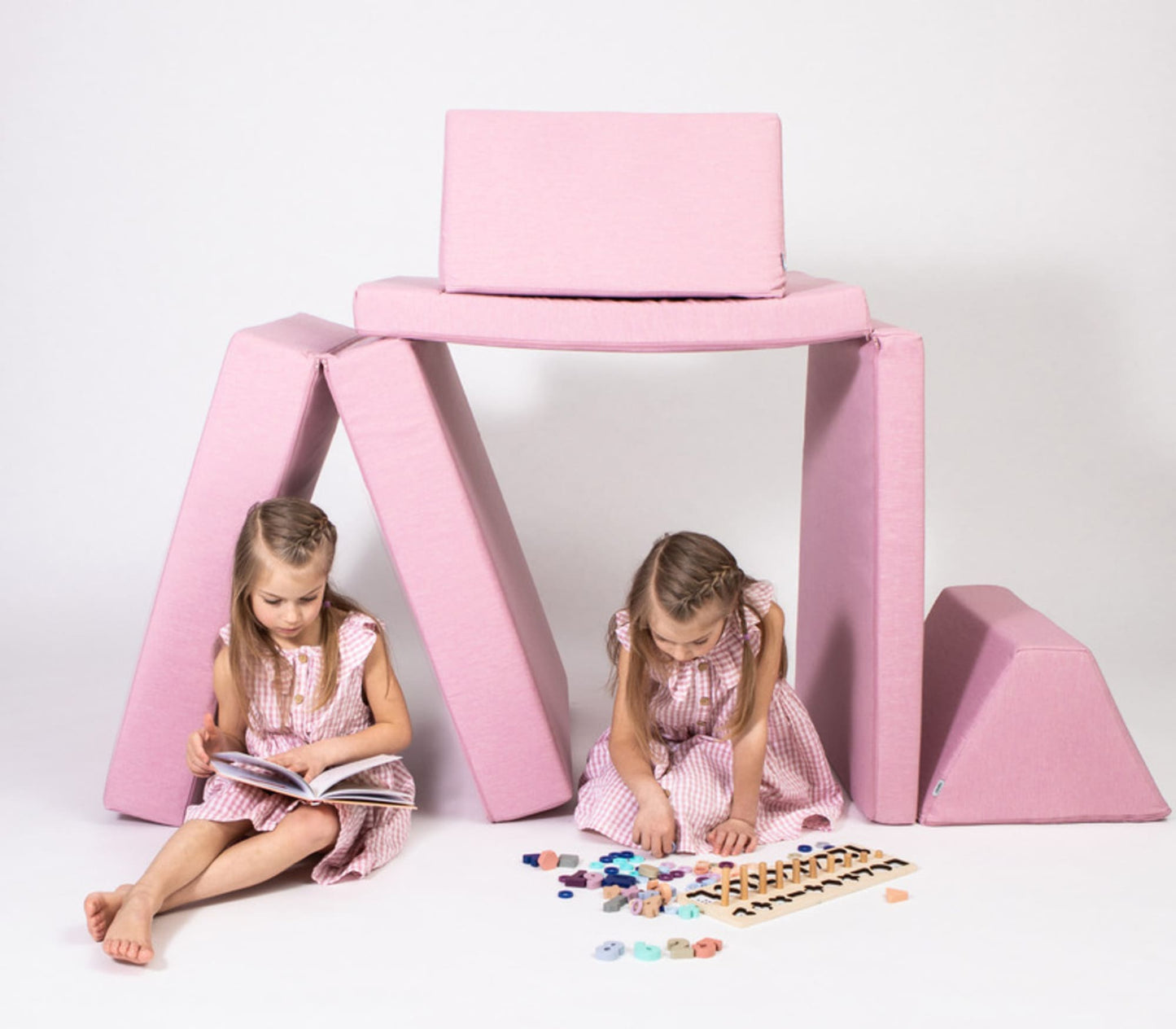 Two kids in matching outfits enjoy open-ended play with vibrant blocks next to a Monboxy Foam play mattress set - Pink, all set against a pristine white background.