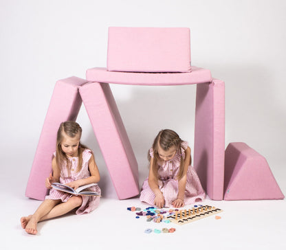 Two kids in matching outfits enjoy open-ended play with vibrant blocks next to a Monboxy Foam play mattress set - Pink, all set against a pristine white background.