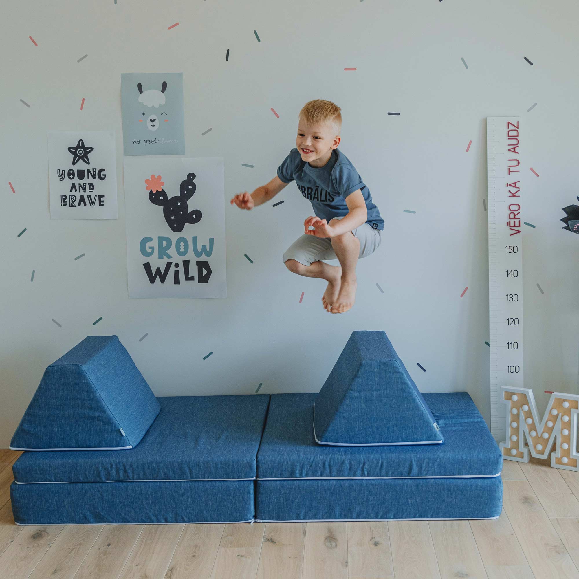 A boy jumping high above a turquoise Monboxy play sofa set for kids